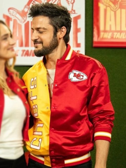 Person wearing a red and yellow sports jacket with a logo in an indoor setting.