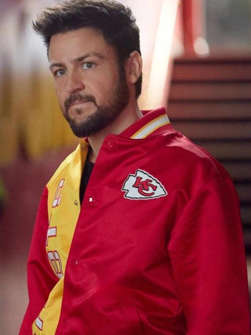 Man wearing a red sports jacket with a logo, standing outdoors.