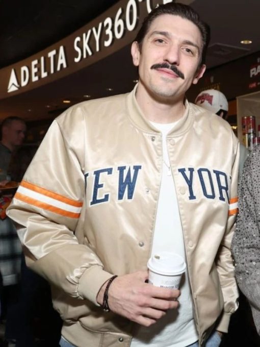 Man wearing a 'New York' jacket holding a white object in an indoor setting with a Delta Sky360 sign.