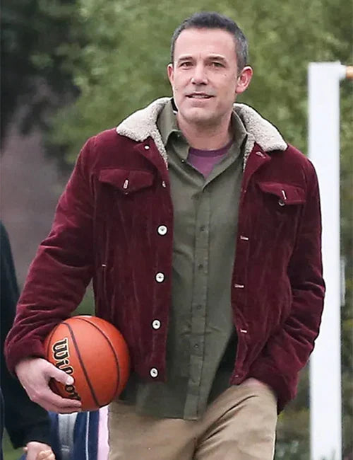 Man holding a basketball wearing a maroon jacket with a white collar.