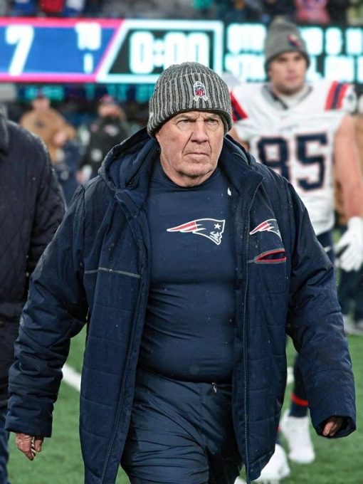 Man wearing a navy jacket with a sports team logo on a football field