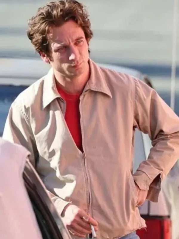 Man wearing a light-colored jacket over a red shirt, standing next to a car.