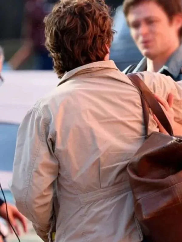 Person wearing a beige jacket with a brown bag, blurred background
