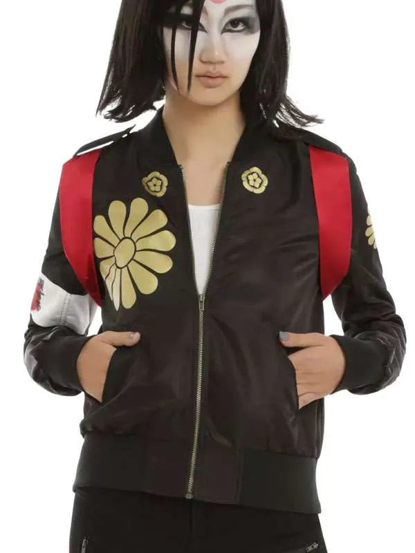 Person wearing a black jacket with gold floral designs and red straps on a white background