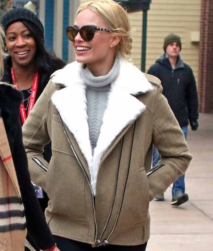 Woman wearing a beige coat with white fur lining on a sidewalk.