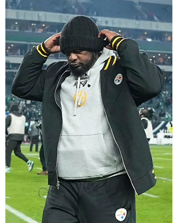 Person wearing a sports team jacket and hoodie on a sports field