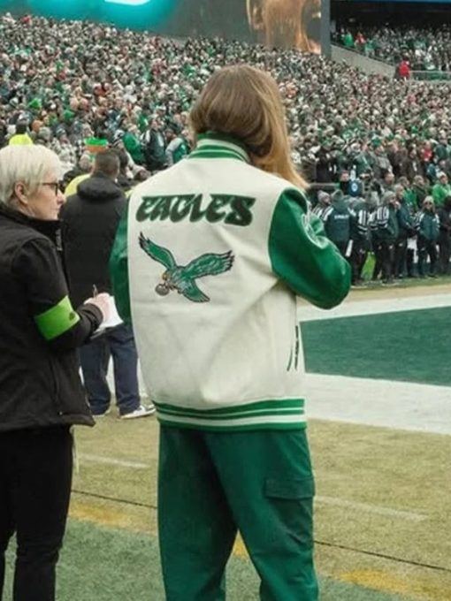 Person wearing a green and white sports jacket with 'Eagles' branding on a sports field.