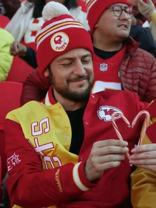Man wearing a red sports team beanie and jacket with candy canes, surrounded by other fans.