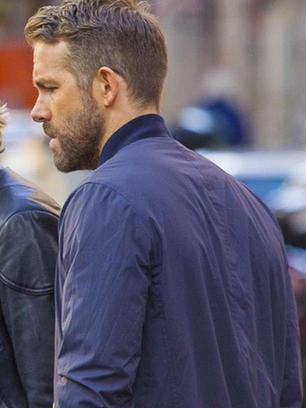 Man wearing a blue jacket in an outdoor setting with blurred background