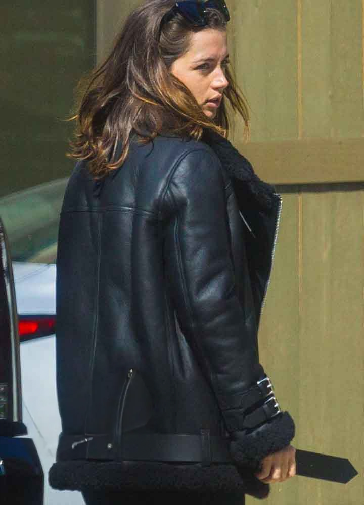 Person wearing a black leather jacket with fur trim outdoors