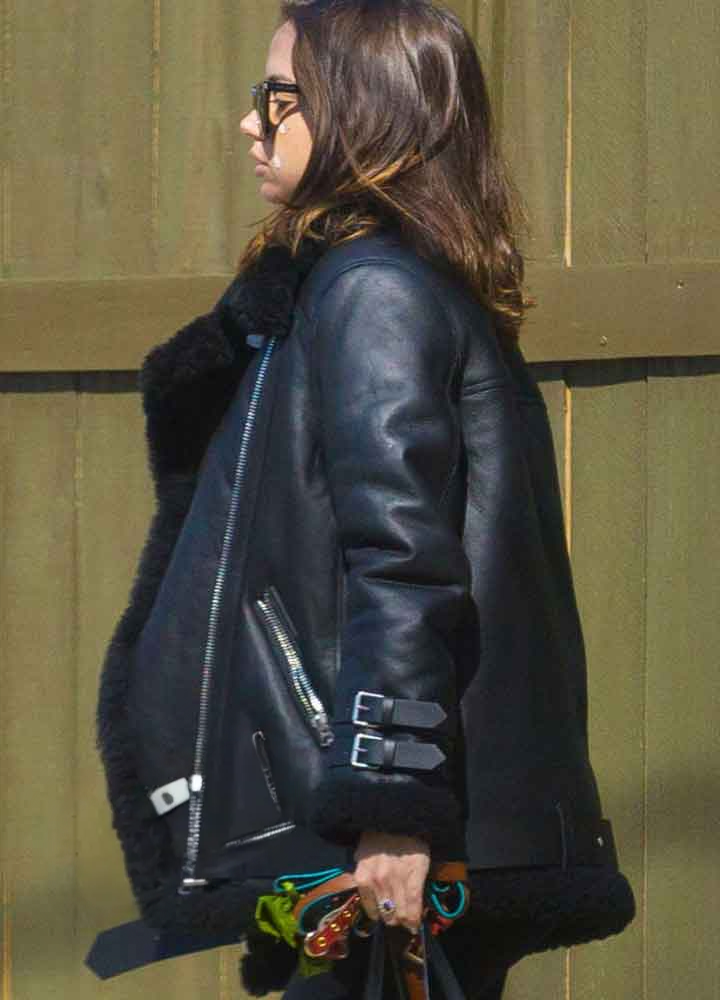 Person wearing a black leather jacket against a green wall